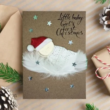 Handmade personalised 1st Christmas card featuring a baby girl made of white feathers - personalised first Christmas card.