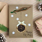 Handmade Personalised Christmas card featuring a dried orange slice, white stars, and a bow.