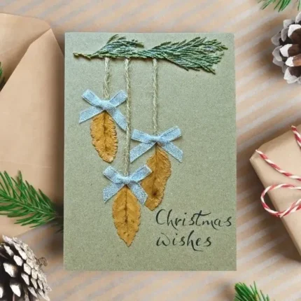 Best Rustic Handcrafted Christmas card with three dried leaves and blue bows and Christmas wishes.