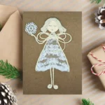 Handmade Christmas Card to Dad from Daughter. The girl made of lace in the image is holding a snowflake.