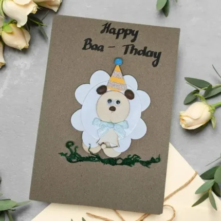Cute Handmade Sheep Birthday Card made of wood and paper with text happy baa-thday on brown paper.
