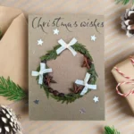 Handmade Festive Wreath Christmas Card with foliage wreath, star anise, and ribbon on brown paper.