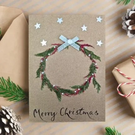 Wreath Christmas Card idea featuring a handmade, embroidered red and green wreath with a silver bow.