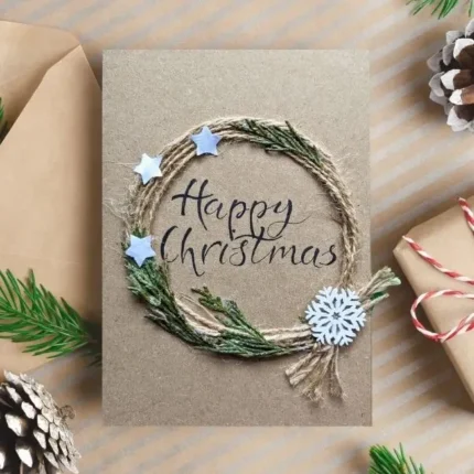 Handmade Happy Christmas Card with a twine wreath, three stars, wooden snowflake and text Happy Christmas.