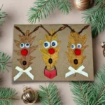 Three reindeer faces on a Hilarious Reindeer Family Holiday Card, surrounded by pine needles, conveying a humorous family theme.