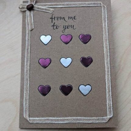 Elegant handmade Valentines Day card featuring purple and white paper hearts, lying on a table. Made in Bollington, UK.