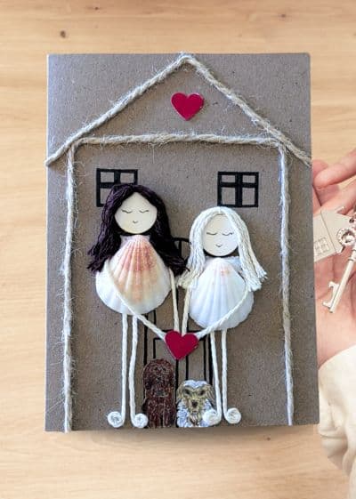 Handmade new home card showing two women with a key and house, representing shared joy and experiences in their new home.