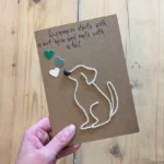 A handmade unique birthday card for dog lovers with a graphic depicting a dog on a string, held in a hand.
