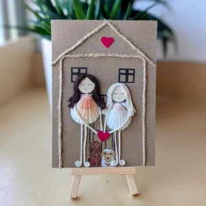 Personalised new home card with two figures made from seashells, twine, and a pink heart 1.