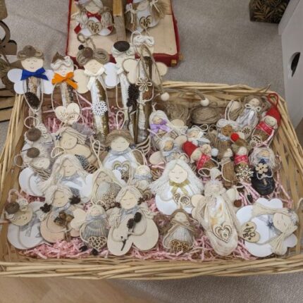 A basket filled with handmade ornaments, including handmade shell angels and various decorative items.