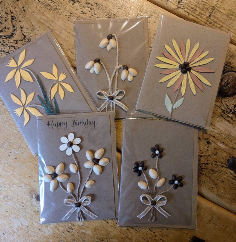 Four handmade loral cards displayed on a table, featured on the Heart in Creation Contact Us page.